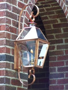 an old fashioned lantern hanging on the side of a brick building with a candle in it