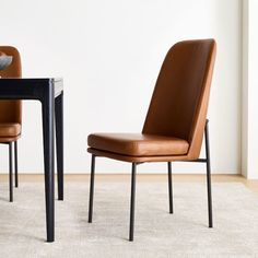 two brown chairs sitting next to each other in front of a table with a bowl on it