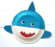 a paper plate shaped like a shark with eyes and teeth on it's face