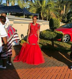 a woman in a red dress standing next to some people