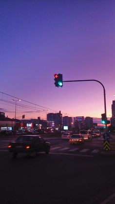 a traffic light hanging over a street filled with cars at sunset or sunrise time in the city