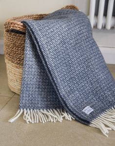 a blue and white blanket sitting on top of a floor next to a basket