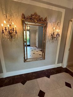 a large mirror hanging on the wall in a room with chandelier and tiled floor