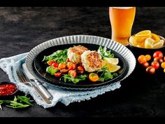 a black plate topped with meat and veggies next to a glass of beer