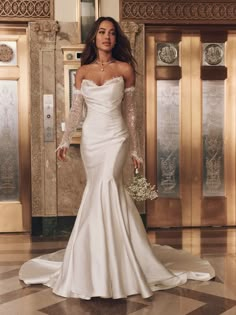 a woman in a white wedding dress is posing for the camera with her hands on her hips