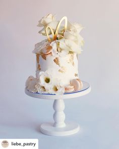 there is a white cake with flowers on the top and gold letters on the bottom