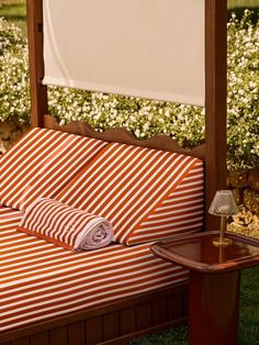 an orange and white striped couch sitting on top of a grass covered field next to a lamp