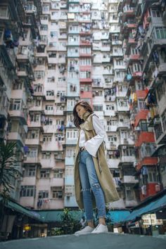 a woman standing in front of a tall building with balconies on the sides