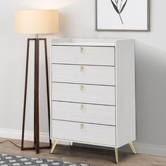 a white chest of drawers next to a lamp