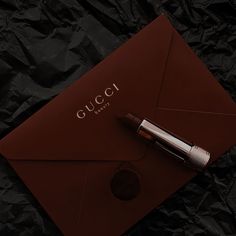 an envelope with a pen on it and the word gucci written in cursive writing