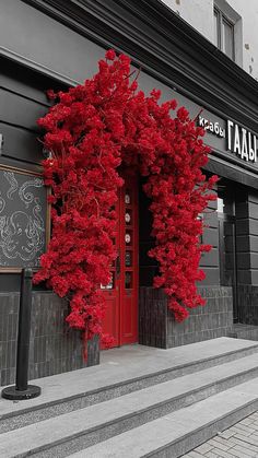 a red tree is in front of a store with stairs leading up to the door