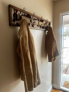 two coats hanging on a coat rack next to a window