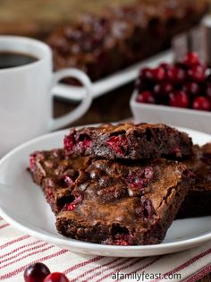 chocolate cranberry brownies on a plate with coffee and cherries in the background