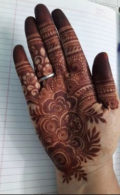 a person's hand with henna tattoos on it and writing in a notebook