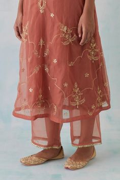 Peach kurta with zari thread, sequin, bead embroidery in floral pattern. Paired with flared pant.
Components: 2
Pattern: Embroidery
Type Of Work: Zari thread, sequin, bead
Neckline: Boat neck
Sleeve Type: Bell sleeves
Fabric: Tissue Organza, Chanderi
Color: Peach
Other Details: 
Attached lining
Sheer panelled pant
Length: 
Kurta: 47 inches
Pant: 37 inches
Model height: 5ft 8inches, wearing size M
Approx. product weight: 2 kgs
Occasion: Mehendi and Haldi - Aza Fashions Ankle-length Sharara With Self Design, Traditional Ankle-length Self Design Dupatta, Unstitched Bottoms With Zari Work For Wedding, Festive Straight Kurta Bottoms With Zari Work, Festive Designer Chanderi Bottoms, Festive Designer Bottoms With Gota Work, Traditional Festive Bottoms With Gota Work, Festive Bollywood Pants With Zari Work, Chanderi Pants For Wedding And Eid