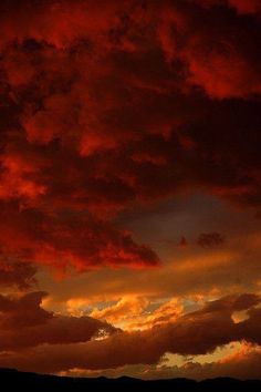 the sky is filled with red clouds as the sun sets