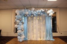 the balloon arch is decorated with silver, white and light blue balloons for an event