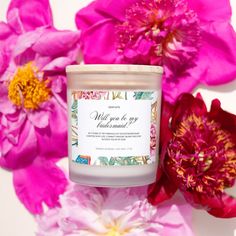 a candle sitting on top of a table next to some pink flowers and peonies