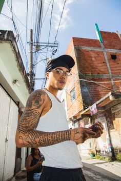 a man with many tattoos on his arm and chest standing in the street next to a building