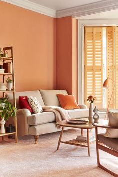 a living room filled with furniture next to a window covered in shutters and blinds