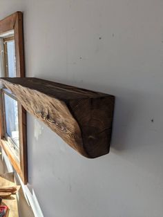 a wooden shelf mounted to the side of a white wall next to a mirror in a room