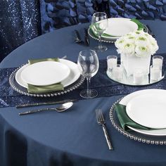 the table is set with white and green plates, silverware, and napkins