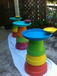 there are many different colored plates on the table together in front of a fenced area