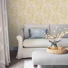 a living room with a couch, ottoman and wallpaper