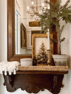 a small christmas tree sitting on top of a wooden shelf in front of a mirror