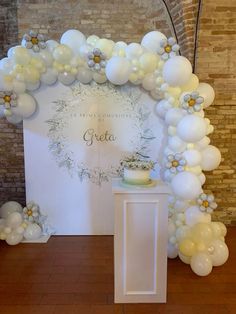 an arch made out of balloons with a cake on the table in front of it