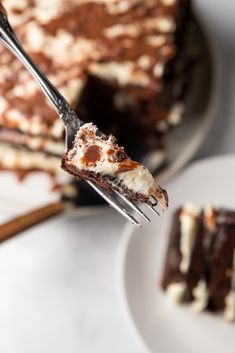 a piece of chocolate cake on a fork with the rest of the cake in the background