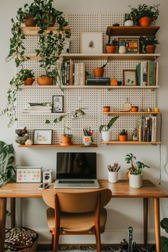 a laptop computer sitting on top of a wooden desk next to a plant filled wall