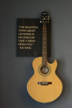 a guitar hanging on the wall next to a sign that says, the beautiful thing about learning is no one can play for you