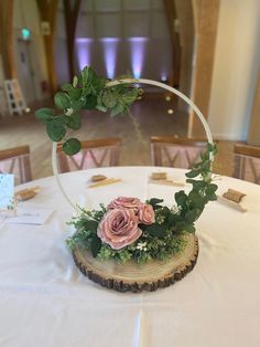 a flower arrangement on top of a wooden slice with greenery and flowers in the center