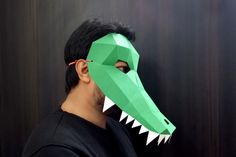 a man wearing a green paper mask with an alligator's mouth