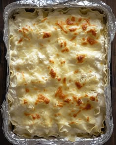 an uncooked casserole dish with cheese and sauce on it sitting on a wooden table