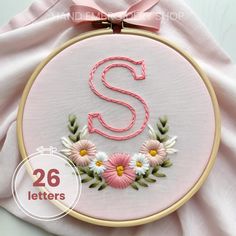 the letter s is surrounded by daisies and leaves in this embroidered monogrammed hoop