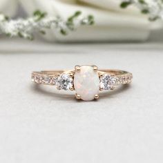 This beautiful ring is made from 14K Solid Rose Gold with Rhodium plating. Ring details- -The Main stone is an oval cut 7mm by 5mm Lab Created White Fire Opal Stone -Side stones are round 3mm and 1.5 clear simulated diamonds -Ring is casted in 14K Solid Rose Gold with Rhodium plating ( 14K Solid Yellow Gold and 14K White Gold also available, please check the drop down menu for more options) -The Total face height of the ring measures 7mms and the band width measures 2mms -Each ring is handmade a Rose Gold Cluster Ring With Round Band For Anniversary, Classic Rose Gold Opal Ring For Anniversary, Rose Gold Halo Ring With Round Cut For Promise, Rose Gold Halo Ring With Prong Setting, Anniversary Rose Gold Cluster Ring With Round Cut, Formal Rose Gold Opal Ring, 14k Rose Gold Round Jewelry With Halo Setting, 14k Rose Gold Jewelry With Halo Setting, 14k Rose Gold Round Halo Jewelry