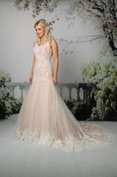 a woman in a wedding dress standing on a white floor next to a wall with flowers