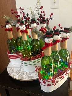 wine bottles decorated with christmas lights and snowmen are sitting in buckets on a table