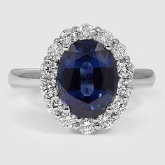 an oval shaped blue sapphire surrounded by white diamonds in a halo setting with two rows of round brilliant cut diamonds surrounding the band