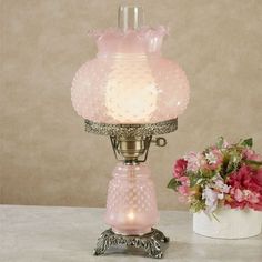 a pink lamp sitting on top of a table next to a vase with flowers in it