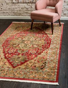 a pink chair sitting on top of a wooden floor next to a rug with an ornate design