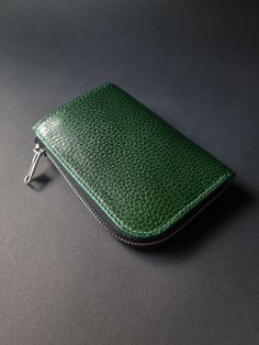 This forest green L-shape wallet is the perfect blend of minimalist design and a warm, natural aesthetic. Crafted from high-quality vegetable-tanned leather, its grained and embossed surface offers a unique texture that evolves beautifully with time and use. The subtle variations in each piece of leather ensure that your wallet is one-of-a-kind, with its character deepening as it ages. Whether you carry it in a backpack, pocket, or purse, this wallet is designed to protect your cash and cards se Modern Green Wallet For Business, Green Leather Card Holder For Everyday Use, Green Wallets With Interior Card Slots, Green Leather Business Wallets, Everyday Green Wallets With Interior Card Slots, Green Leather Wallet With Zipper Closure, Green Leather Wallets With Zipper Closure, Modern Green Leather Wallets, Modern Green Leather Wallet