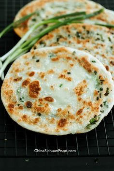 three flat breads on a cooling rack with green onions