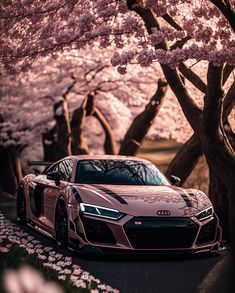 a pink sports car parked in front of cherry blossom trees with the sun shining on them