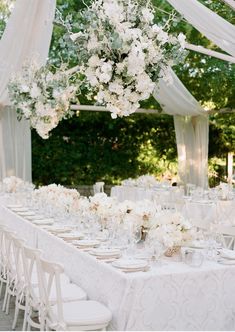 an outdoor wedding reception with white flowers and hanging chandelier over the head table