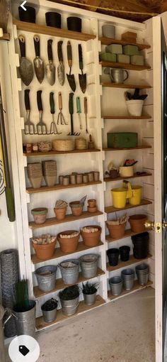 an open storage area with pots and pans on the shelves in front of it