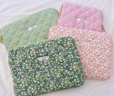 four flowered pouch bags sitting on top of a white sheet