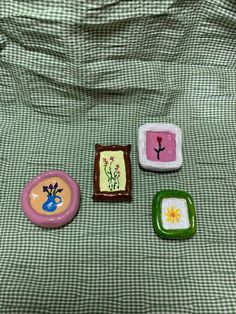 three small plates sitting on top of a green tablecloth covered bed with white and pink designs